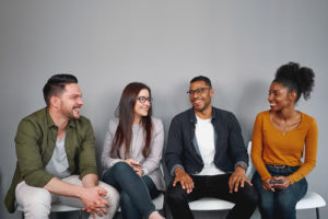 Four students sit in chairs talking, a sign that they feel connected on campus.