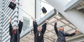 Three students tossing graduation caps in the air