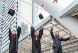Three students tossing graduation caps in the air