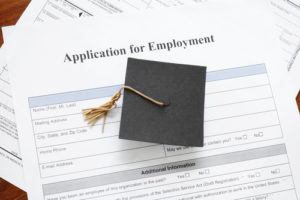 Graduation cap and a job application indicating the need for life skills.