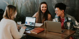 College students sitting at a table with laptops open