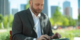 An adult student, in a suit, working on a tablet.