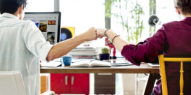 Two students doing a fist bump while taking online classes