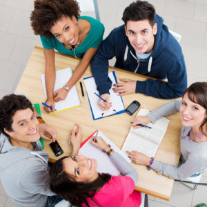 A group of multi-ethnic college students studying at a wooden table