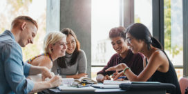 a group of happy, healthy-looking college students studying at a table