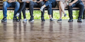 Students sit on a bench with laptops as they participate in their online learning programs.