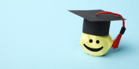 a happy face stuffed emoji wearing a graduation cap