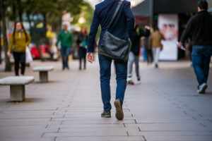 Rear view of a college student with a messenger bag walking to work.
