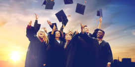 a group of first-generation college students in graduation gowns, throwing their caps in the air