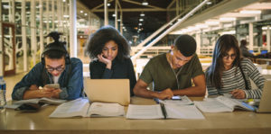 College students sit in a row as 4-year universities try to grow their community college pipeline.