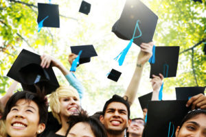 Community college students throw their hats in the air in celebration.