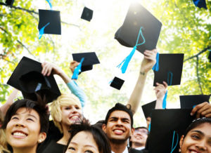 Community college students throw their hats in the air in celebration.