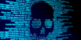 A skull on a coding screen indicates malware, illustrating the need for strong cybersecurity education programs.