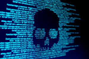 A skull on a coding screen indicates malware, illustrating the need for strong cybersecurity education programs.
