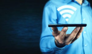 A man holds a device with a campus wi-fi symbol above it.