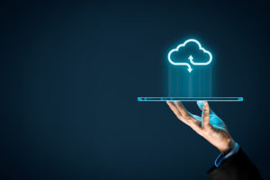 A hand holding a tablet with a cloud above to symbolize cloud computing shows how to handle challenges that may accompany a transition to Azure Active Directory.