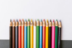 A line of smiling different colored pencils represents diversity.