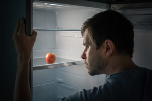 A man peers into the fridge and sees only an apple. A new report details the variables that influence how food insecurity can fluctuate for many college students.