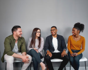 Four students sit in chairs talking, a sign that they feel connected on campus.