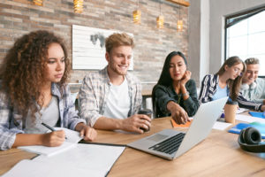 A new report sheds light on how institutions can best meet the tech needs and expectations of students, like these college students sitting together working on laptops in the library.