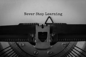 A typewriter with the words Never Stop Learning typed on a piece of paper demonstrates lifelong learning.